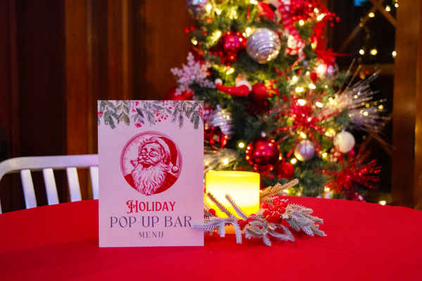 a card on a table with a lit candle and a tree in the background